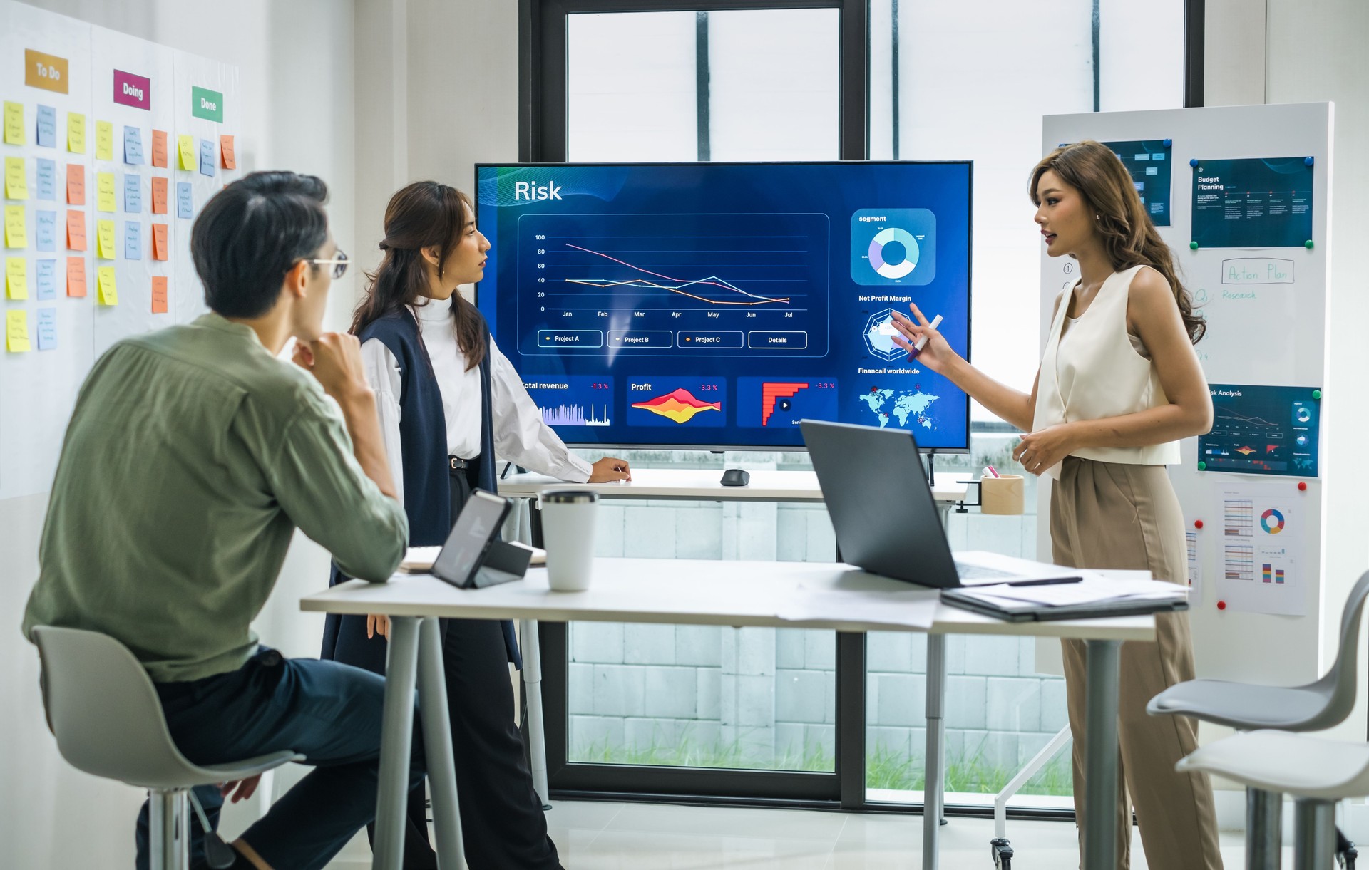 asian worman leader presenting a financial data and strategies in a modern office with charts and graphs displayed on a large screen